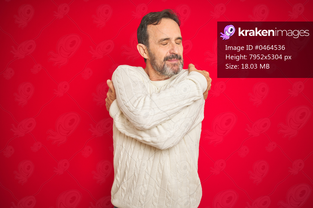 Handsome middle age senior man with grey hair over isolated red background Hugging oneself happy and positive, smiling confident. Self love and self care