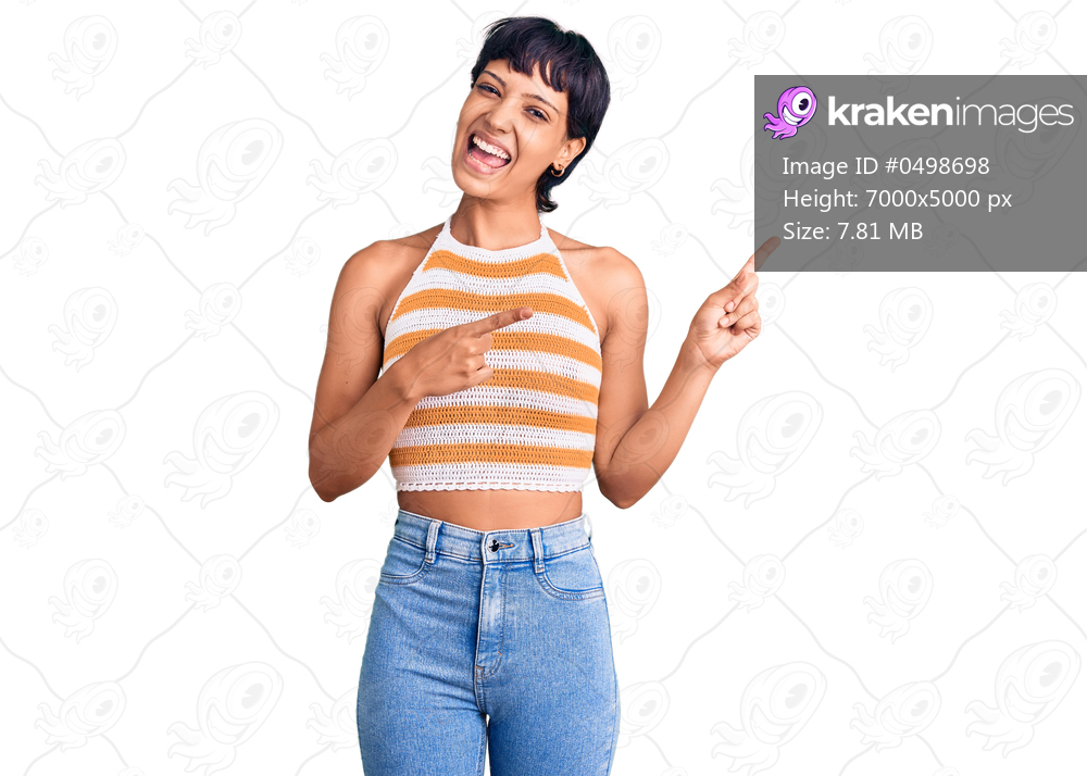 Young brunette woman with short hair wearing casual clothes smiling and looking at the camera pointing with two hands and fingers to the side. 