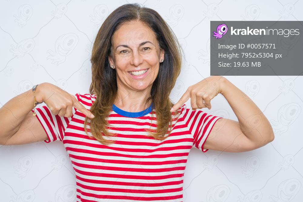 Middle age senior woman standing over white isolated background looking confident with smile on face, pointing oneself with fingers proud and happy.
