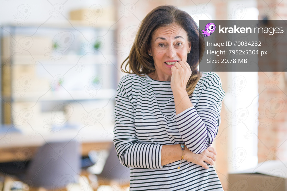 Beautiful middle age senior woman standing looking stressed and nervous with hands on mouth biting nails. Anxiety problem.