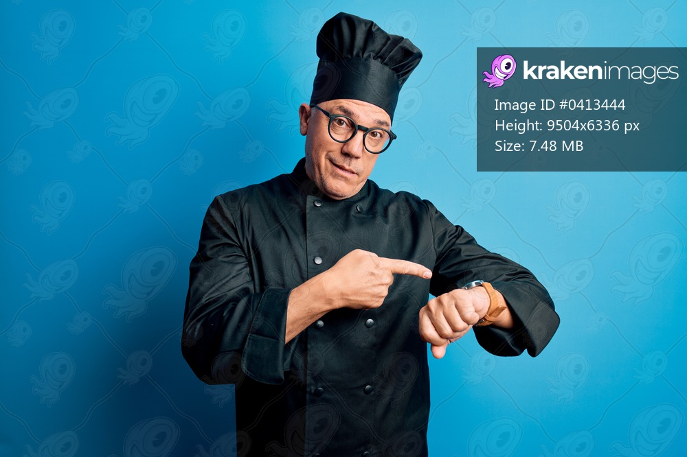 Middle age handsome grey-haired chef man wearing cooker uniform and hat In hurry pointing to watch time, impatience, upset and angry for deadline delay