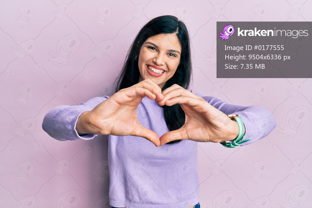 Young hispanic woman wearing casual clothes smiling in love doing heart symbol shape with hands. romantic concept. 