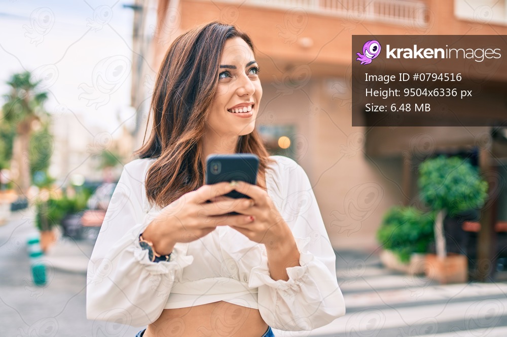Young hispanic woman smiling happy using smartphone at the city.