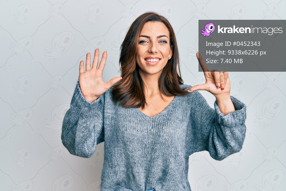 Young brunette woman wearing casual winter sweater showing and pointing up with fingers number seven while smiling confident and happy. 