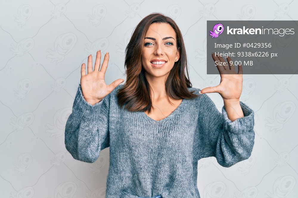 Young brunette woman wearing casual winter sweater showing and pointing up with fingers number ten while smiling confident and happy. 