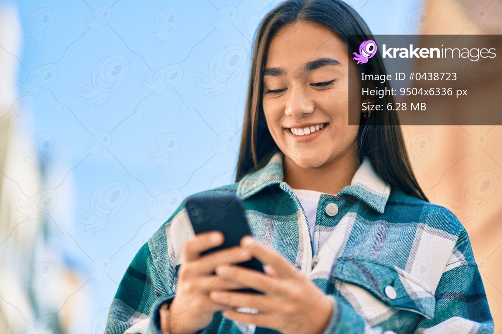 Young latin girl smiling happy using smartphone at the city.