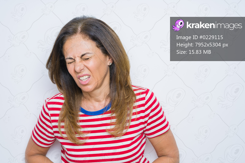 Middle age senior woman standing over white isolated background with hand on stomach because indigestion, painful illness feeling unwell. Ache concept.