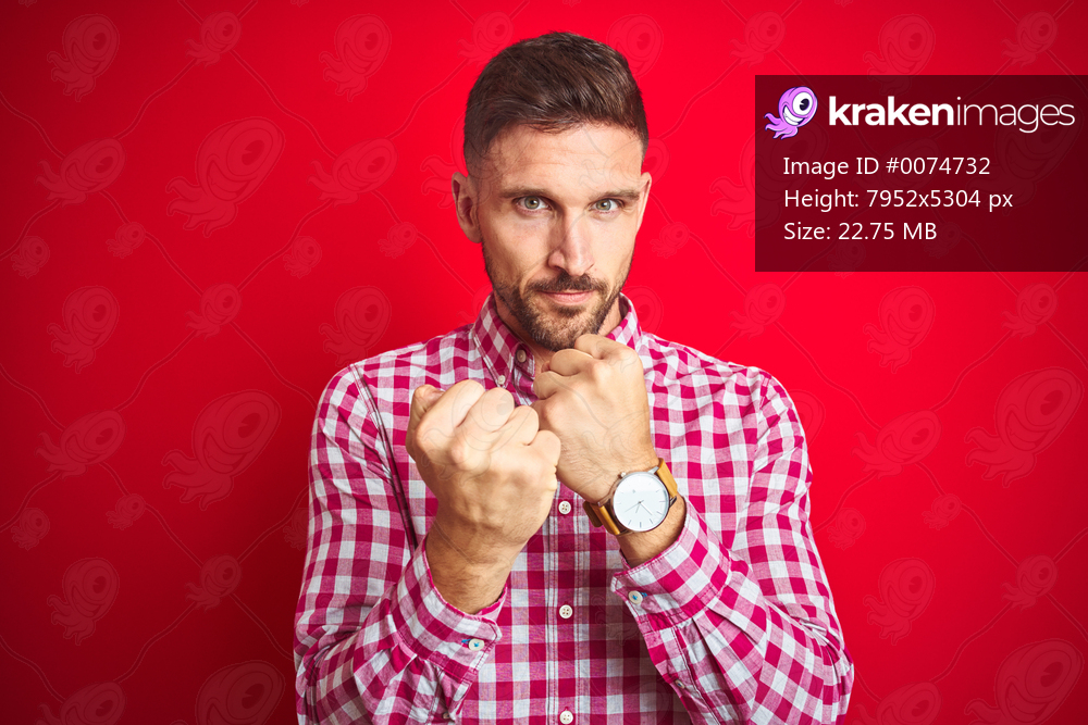 Young handsome man over red isolated background Ready to fight with fist defense gesture, angry and upset face, afraid of problem