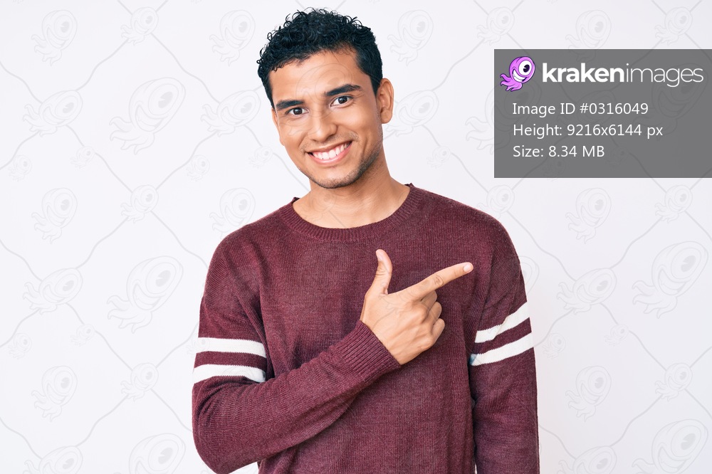 Young handsome hispanic man over white background smiling cheerful pointing with hand and finger up to the side 