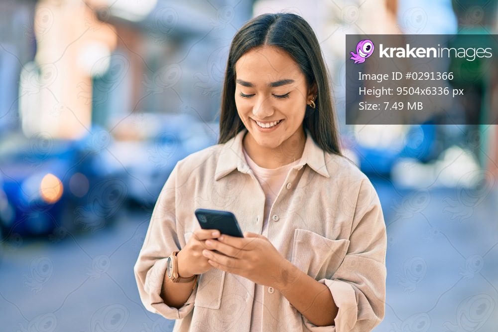 Young latin girl smiling happy using smartphone at the city.