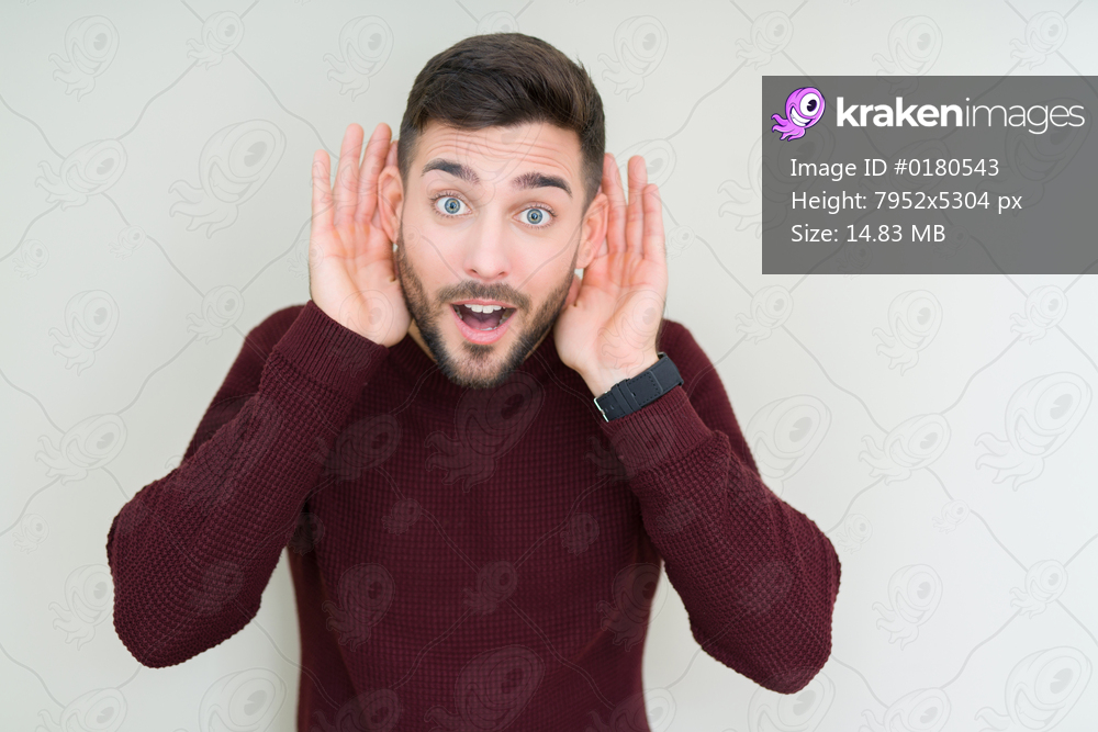 Young handsome man wearing a sweater over isolated background Trying to hear both hands on ear gesture, curious for gossip. Hearing problem, deaf