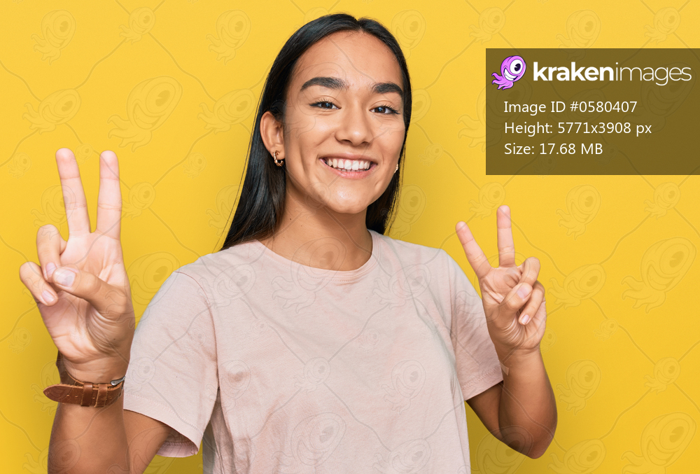 Young asian woman wearing casual clothes smiling looking to the camera showing fingers doing victory sign. number two. 