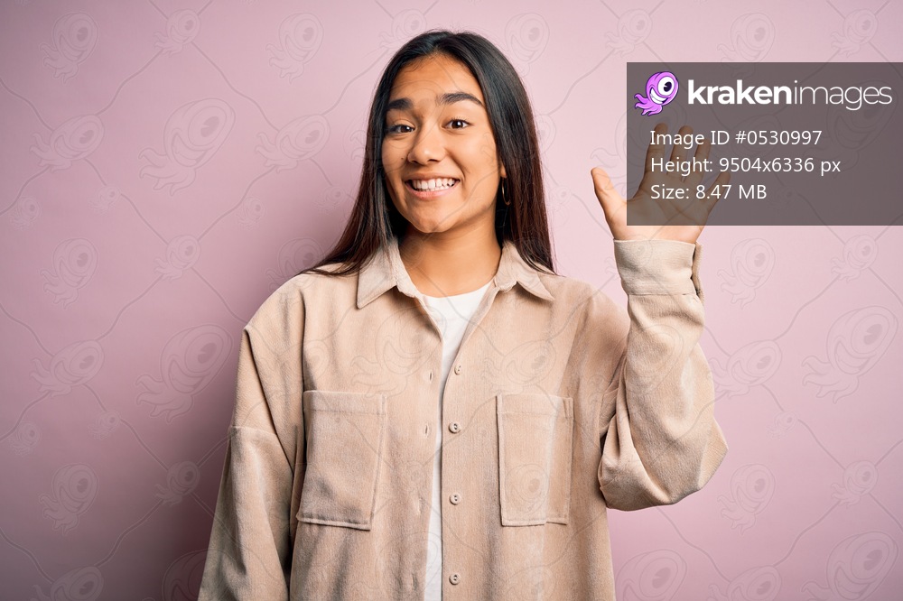 Young beautiful asian woman wearing casual shirt standing over pink background showing and pointing up with fingers number five while smiling confident and happy.