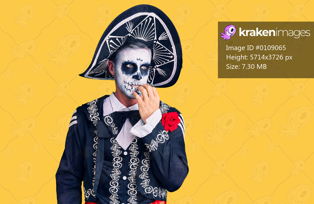 Young man wearing day of the dead costume over background looking stressed and nervous with hands on mouth biting nails. anxiety problem. 