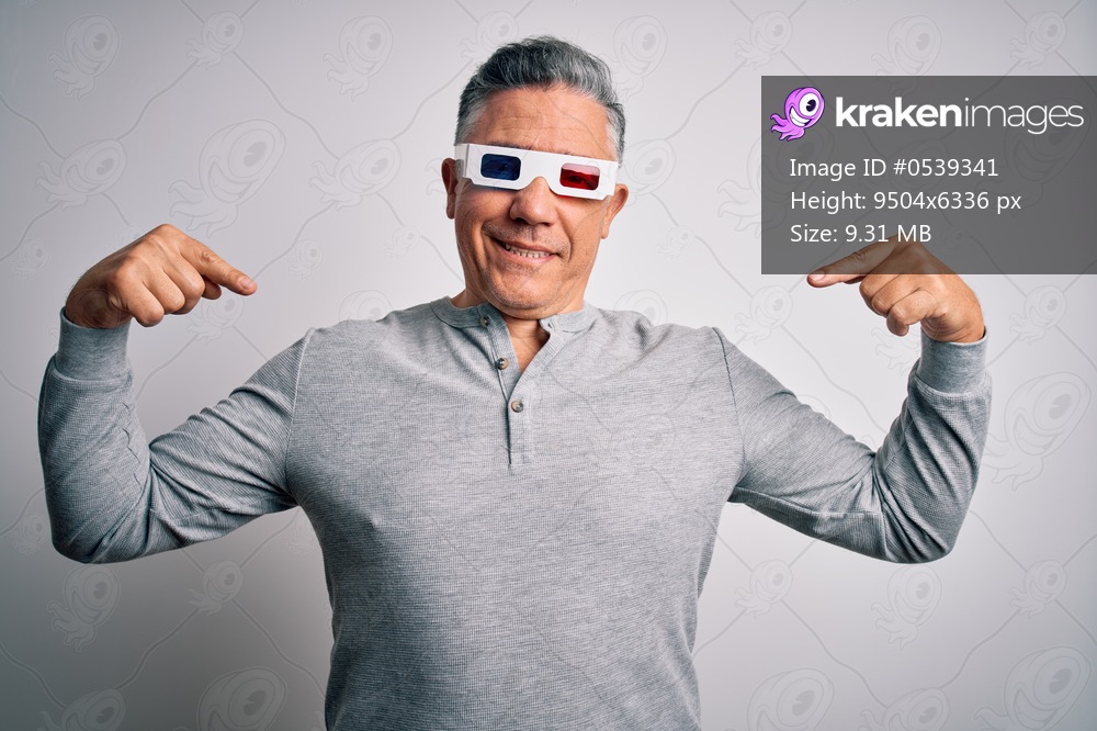 Middle age handsome grey-haired man using 3d glasses over isolated white background looking confident with smile on face, pointing oneself with fingers proud and happy.