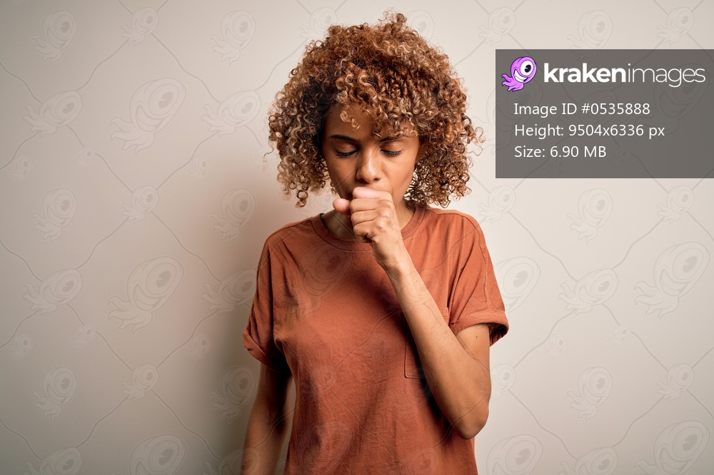 Beautiful african american woman with curly hair wearing casual t-shirt over white background feeling unwell and coughing as symptom for cold or bronchitis. Health care concept.