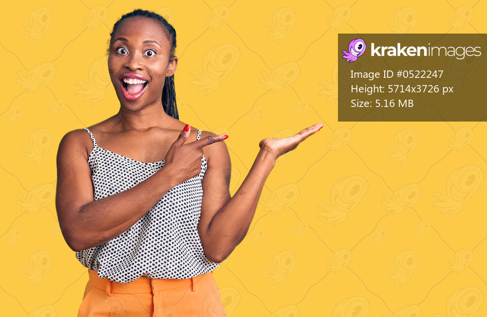 Young african american woman wearing casual clothes amazed and smiling to the camera while presenting with hand and pointing with finger. 