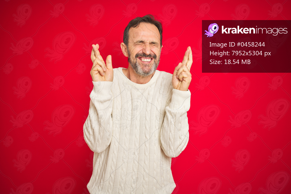 Handsome middle age senior man with grey hair over isolated red background gesturing finger crossed smiling with hope and eyes closed. Luck and superstitious concept.