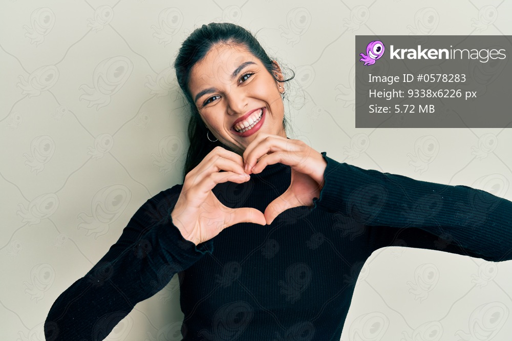 Young hispanic woman wearing casual clothes smiling in love doing heart symbol shape with hands. romantic concept. 