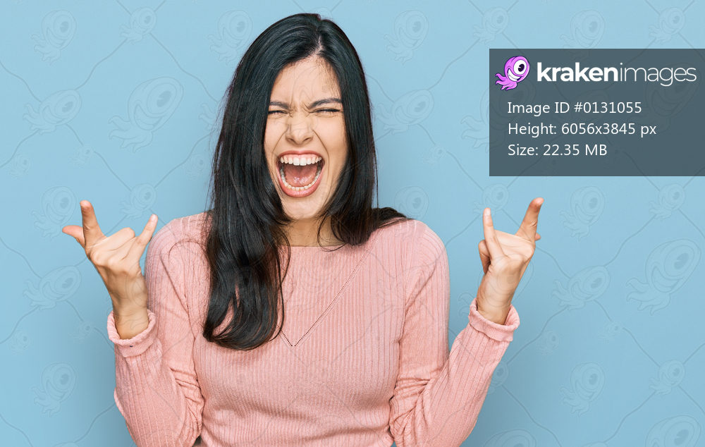 Young hispanic woman wearing casual clothes shouting with crazy expression doing rock symbol with hands up. music star. heavy concept. 