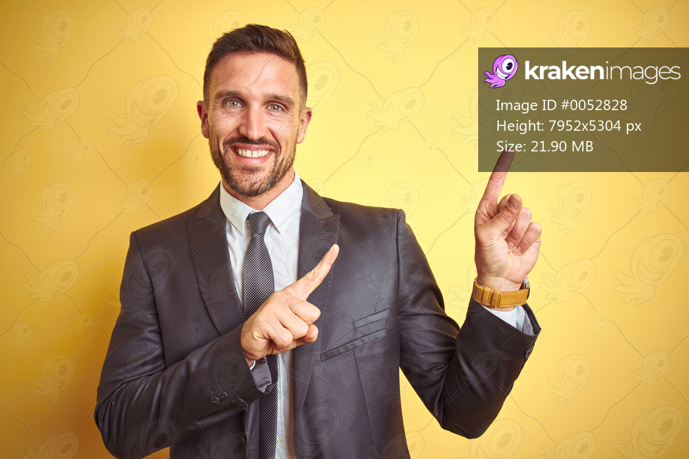 Young handsome business man over yellow isolated background smiling and looking at the camera pointing with two hands and fingers to the side.