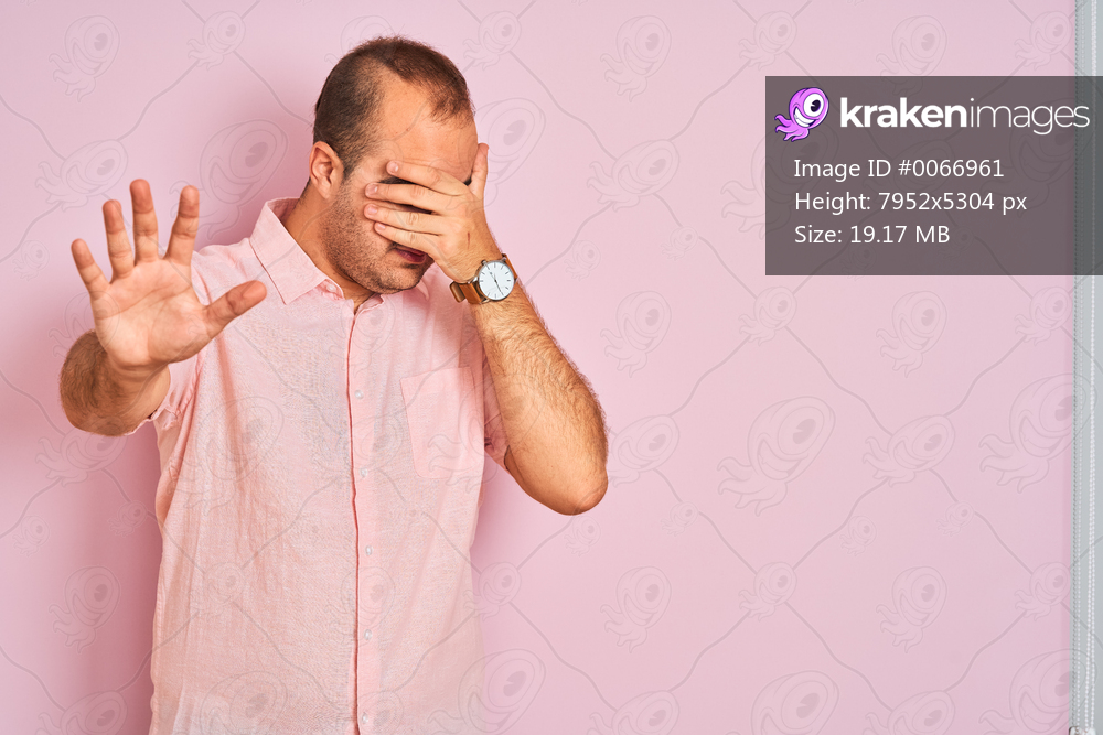 Young man wearing elegant shirt standing over isolated pink background covering eyes with hands and doing stop gesture with sad and fear expression. Embarrassed and negative concept.