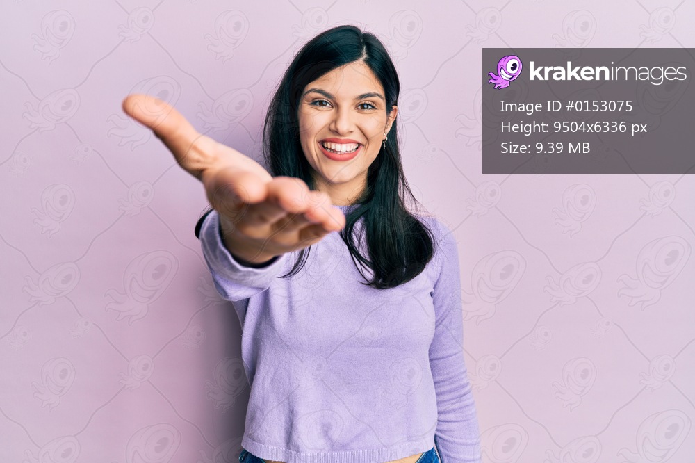 Young hispanic woman wearing casual clothes smiling cheerful offering palm hand giving assistance and acceptance. 