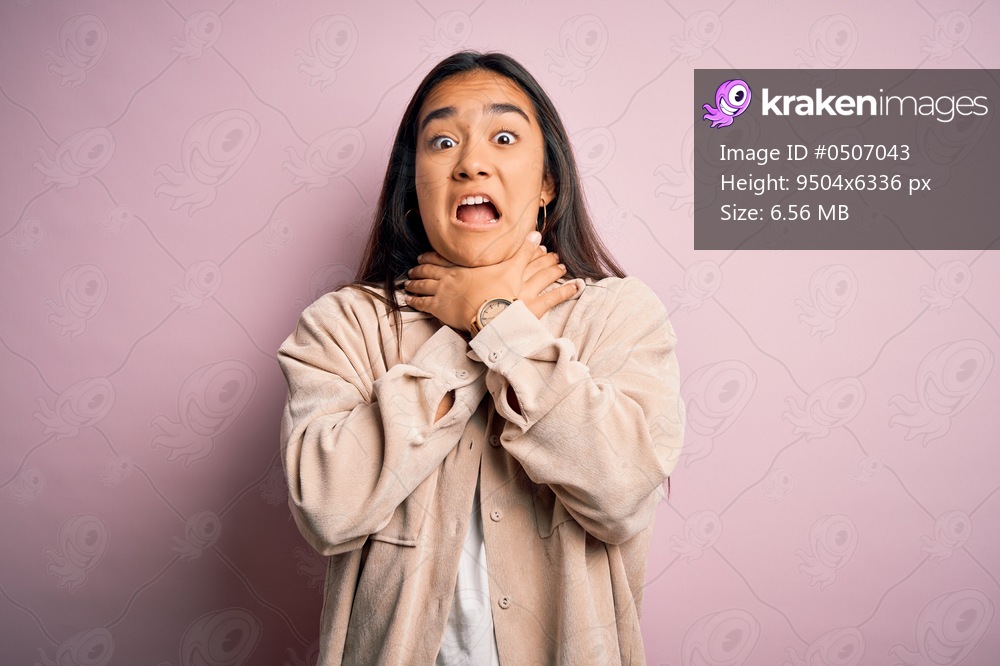 Young beautiful asian woman wearing casual shirt standing over pink background shouting suffocate because painful strangle. Health problem. Asphyxiate and suicide concept.