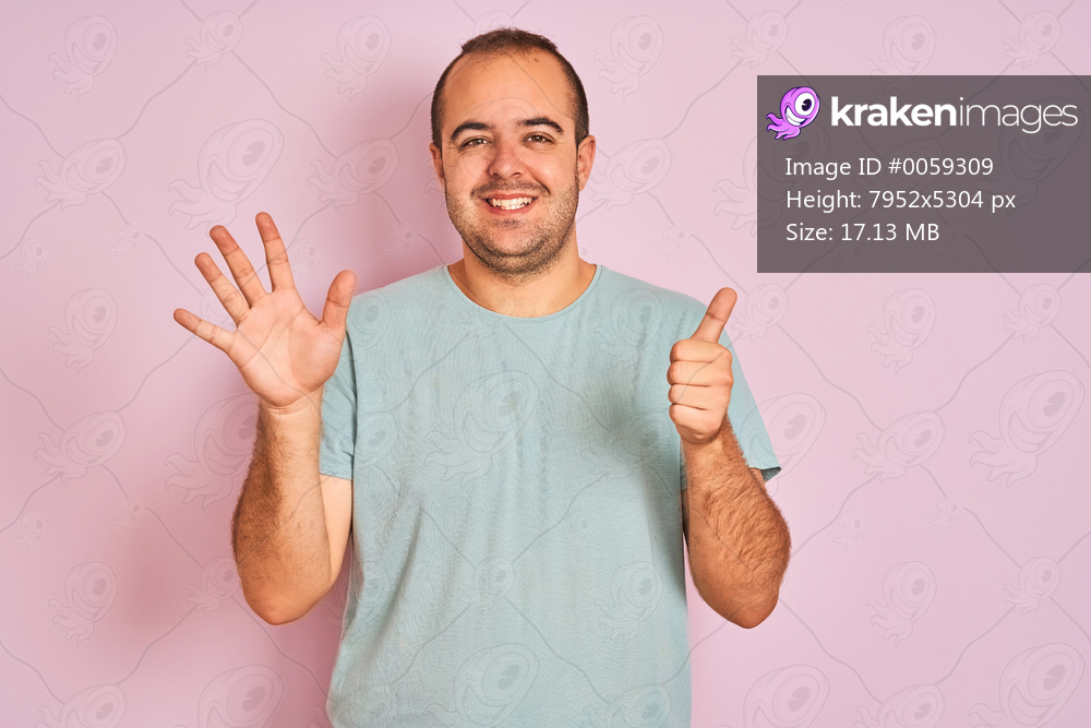 Young man wearing blue casual t-shirt standing over isolated pink background showing and pointing up with fingers number six while smiling confident and happy.