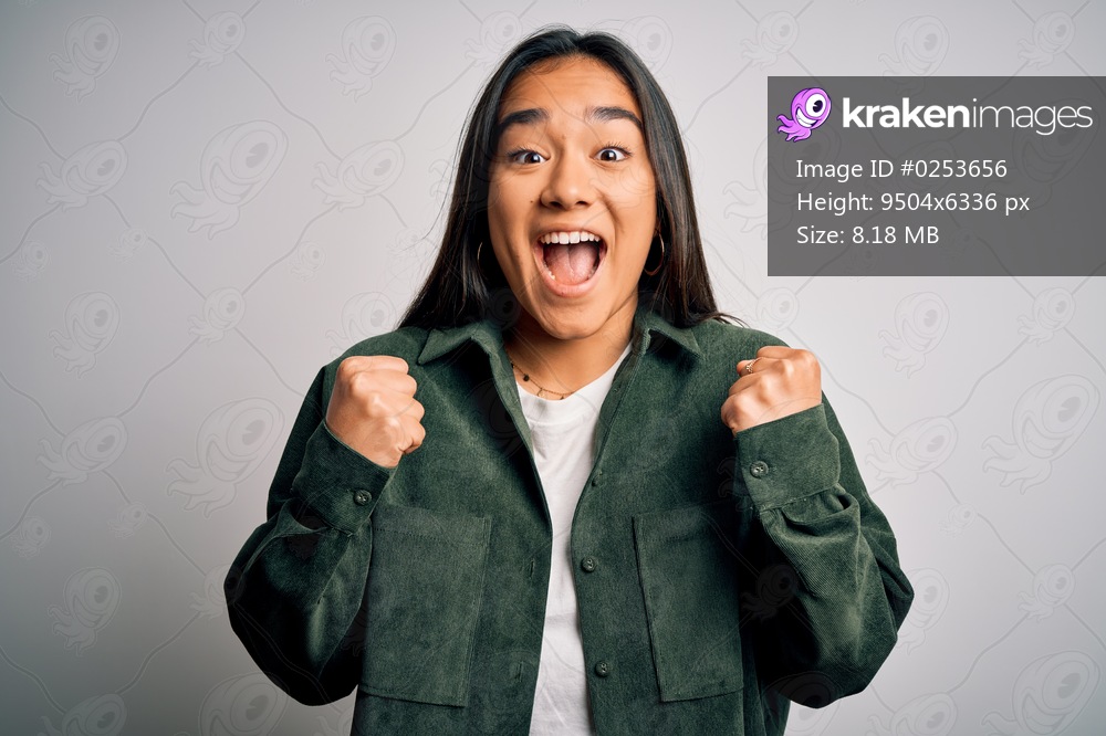 Young beautiful asian woman wearing casual shirt standing over isolated white background celebrating surprised and amazed for success with arms raised and open eyes. Winner concept.