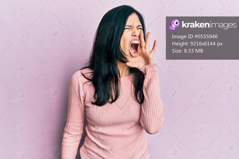 Young hispanic woman wearing casual clothes shouting and screaming loud to side with hand on mouth. communication concept. 