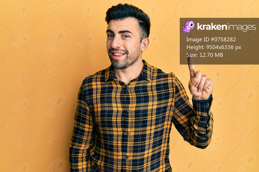 Young hispanic man wearing casual clothes pointing finger up with successful idea. exited and happy. number one. 