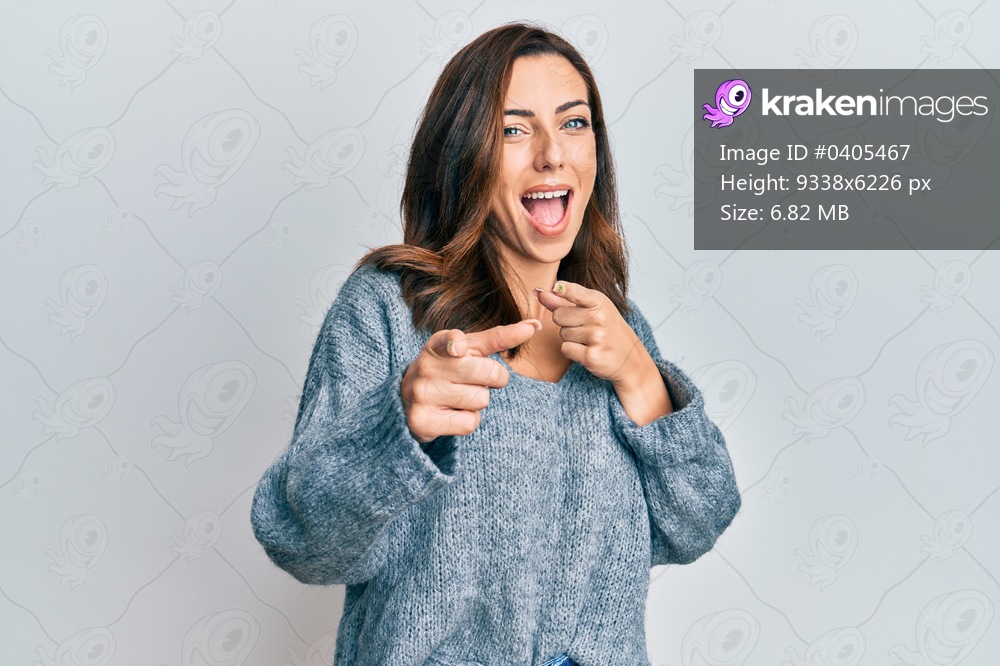 Young brunette woman wearing casual winter sweater pointing fingers to camera with happy and funny face. good energy and vibes. 