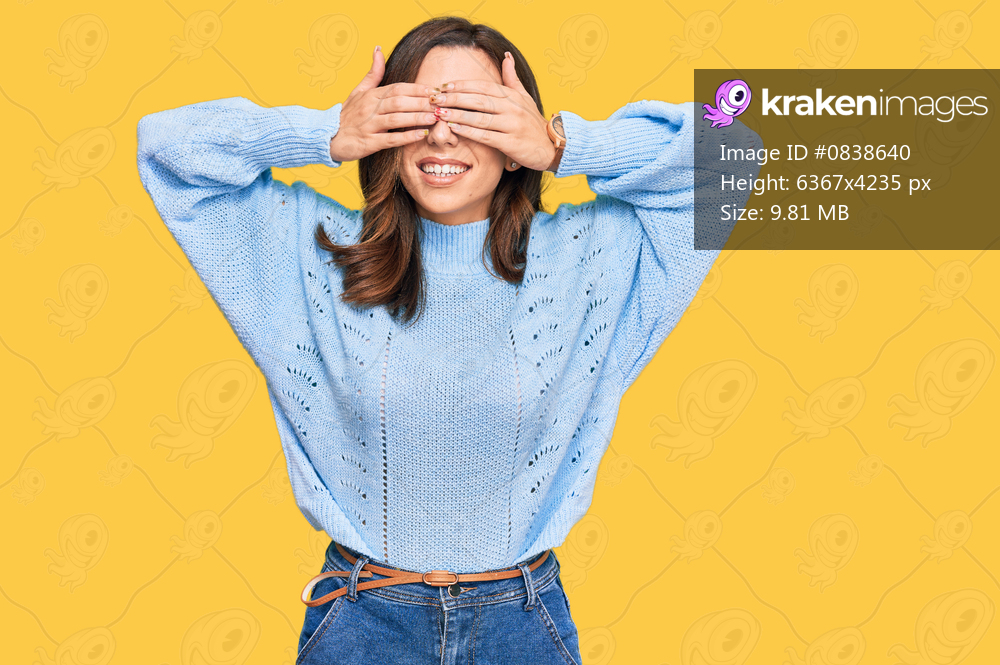 Young brunette woman wearing casual winter sweater covering eyes with hands smiling cheerful and funny. blind concept. 