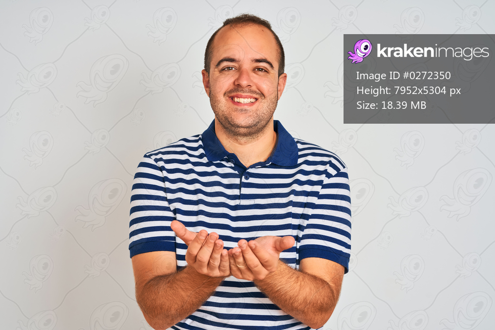 Young man wearing casual striped polo standing over isolated white background Smiling with hands palms together receiving or giving gesture. Hold and protection