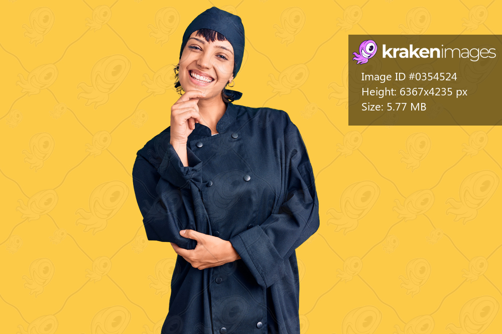 Young brunette woman with short hair wearing professional cook uniform looking confident at the camera with smile with crossed arms and hand raised on chin. thinking positive. 