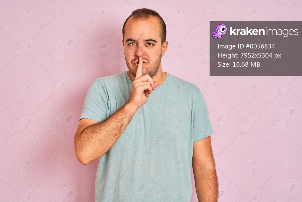 Young man wearing blue casual t-shirt standing over isolated pink background asking to be quiet with finger on lips. Silence and secret concept.
