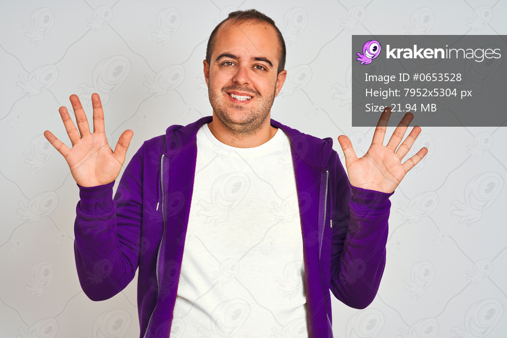 Young man wearing purple sweatshirt standing over isolated white background showing and pointing up with fingers number ten while smiling confident and happy.