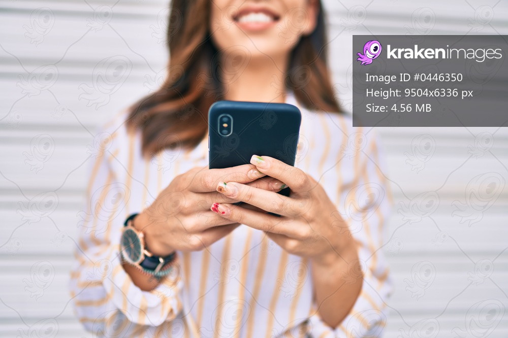 Young hispanic woman smiling happy using smartphone at the city.
