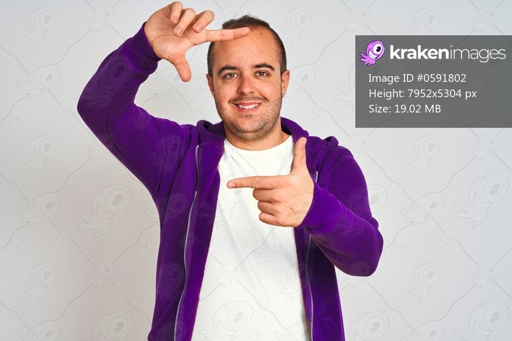 Young man wearing purple sweatshirt standing over isolated white background smiling making frame with hands and fingers with happy face. Creativity and photography concept.