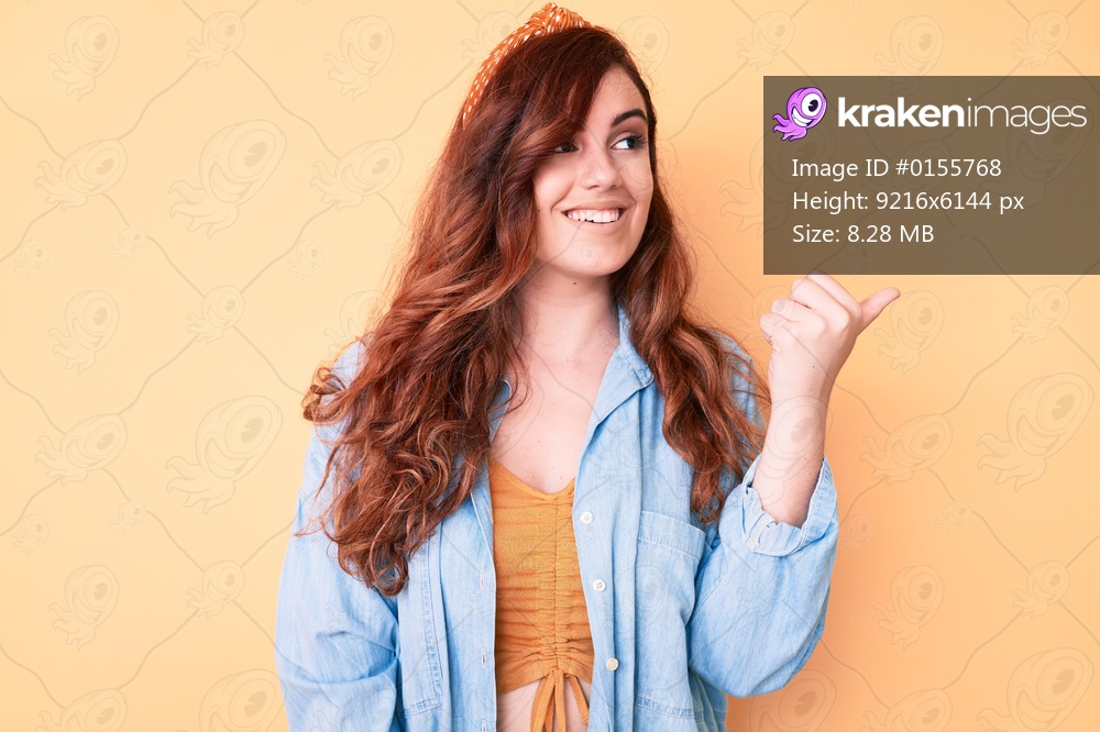Young beautiful woman wearing casual clothes pointing thumb up to the side smiling happy with open mouth 