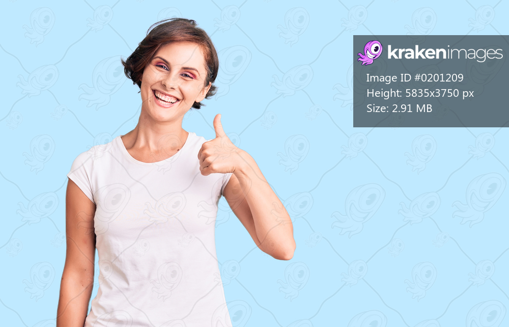 Beautiful young woman with short hair wearing casual clothes smiling happy and positive, thumb up doing excellent and approval sign 