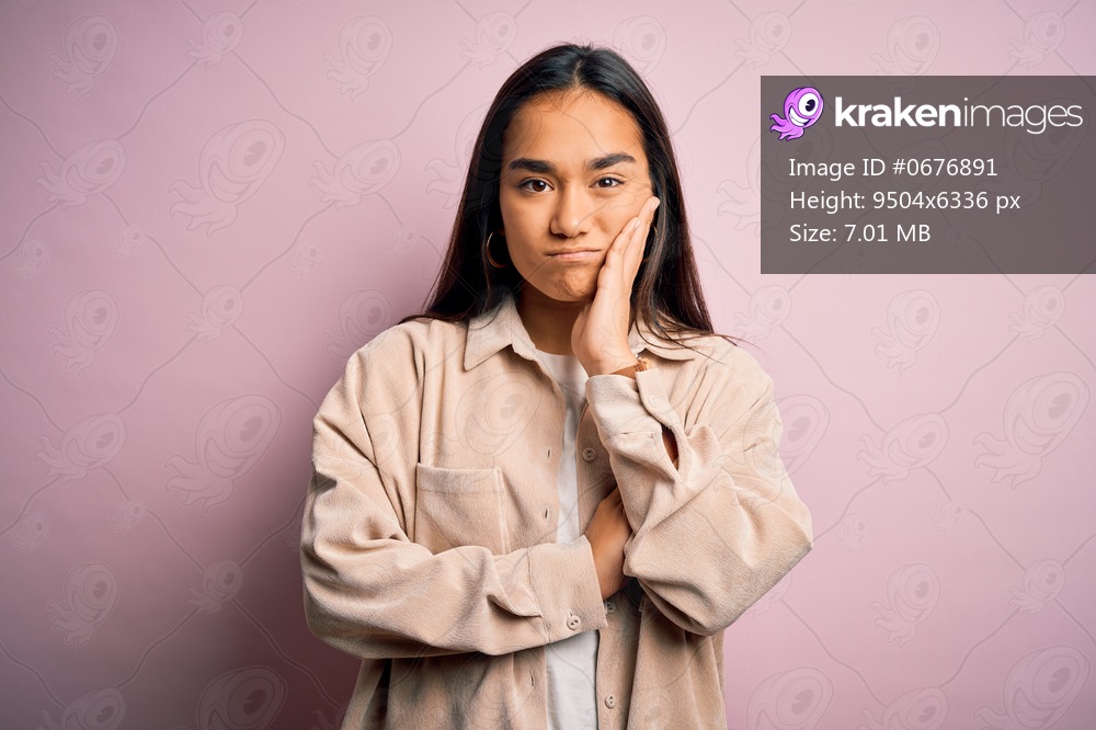 Young beautiful asian woman wearing casual shirt standing over pink background thinking looking tired and bored with depression problems with crossed arms.