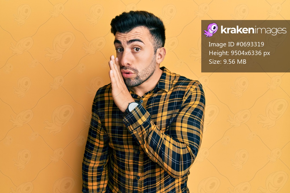 Young hispanic man wearing casual clothes hand on mouth telling secret rumor, whispering malicious talk conversation 