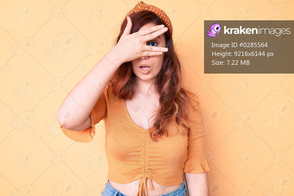 Young beautiful woman wearing casual clothes peeking in shock covering face and eyes with hand, looking through fingers with embarrassed expression. 