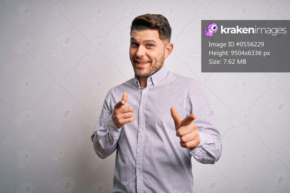 Young business man with blue eyes standing over isolated background pointing fingers to camera with happy and funny face. Good energy and vibes.