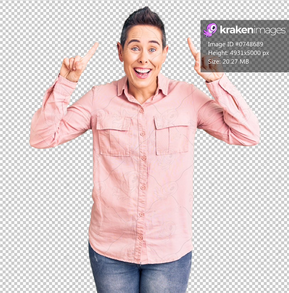Young woman with short hair wearing casual clothes smiling amazed and surprised and pointing up with fingers and raised arms.
