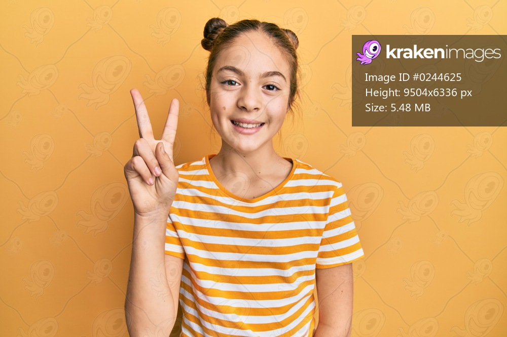 Beautiful brunette little girl wearing casual striped t shirt showing and pointing up with fingers number two while smiling confident and happy. 