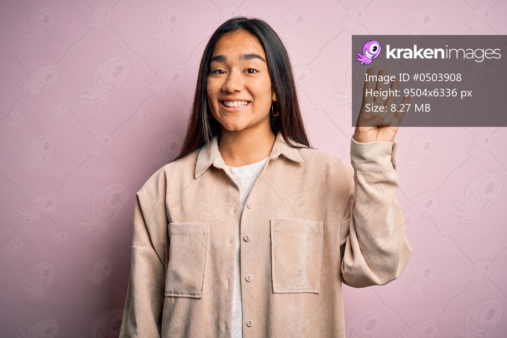 Young beautiful asian woman wearing casual shirt standing over pink background showing and pointing up with fingers number four while smiling confident and happy.