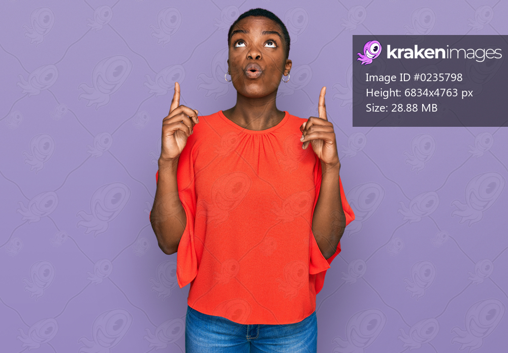 Young african american woman wearing casual clothes amazed and surprised looking up and pointing with fingers and raised arms. 